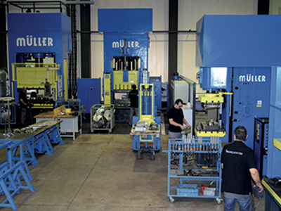 Mehrere große Müller-Stanzpressen in einer industriellen Produktionshalle mit Mitarbeitern bei der Arbeit.